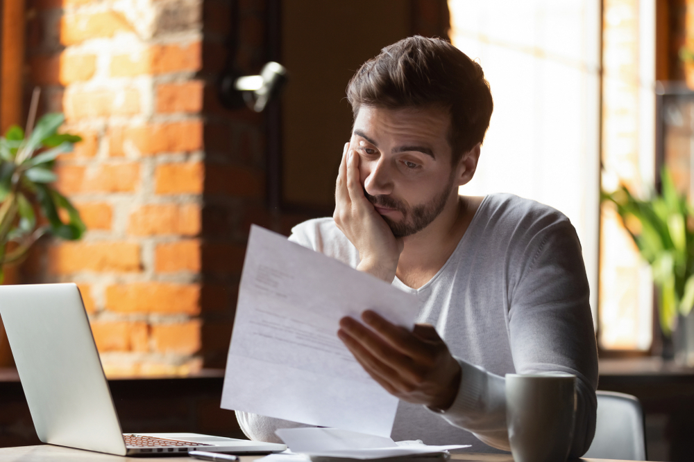 Confused,Frustrated,Young,Man,Reading,Letter,In,Cafe,,Debt,Notification,